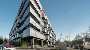 A modern building with a unique angular design, featuring multiple balconies and a prominent sign on the facade. - RentPlanet - Studio Zwycięska (Wroclaw)