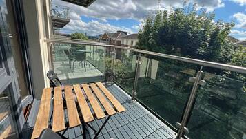 A balcony with a glass railing, a wooden table, and a chair.