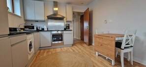 Eine kompakte Küche mit Waschmaschine, Mikrowelle, Backofen und einem Holzespeise Tisch mit Stühlen.