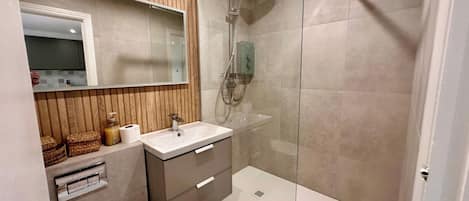 A modern bathroom with a shower, sink, and vanity.