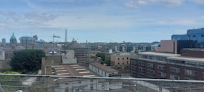 A cityscape with various buildings, including a prominent green-roofed tower, a modern glass building, and older brick structures.