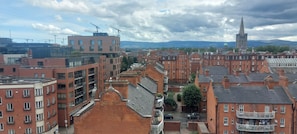 Un paysage urbain où se côtoient une architecture moderne et traditionnelle, avec, au loin, le clocher imposant d’une église.