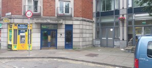 A building with a blue door labeled 'No.20 Christchurch Place' and an ATM on the sidewalk.