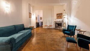 Un amplio salón con suelo de parqué, un sofá azul aguamarina y una chimenea.