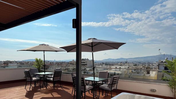 Una terraza en la azotea con mobiliario exterior, una bañera de hidromasaje y vistas a la ciudad y las montañas.