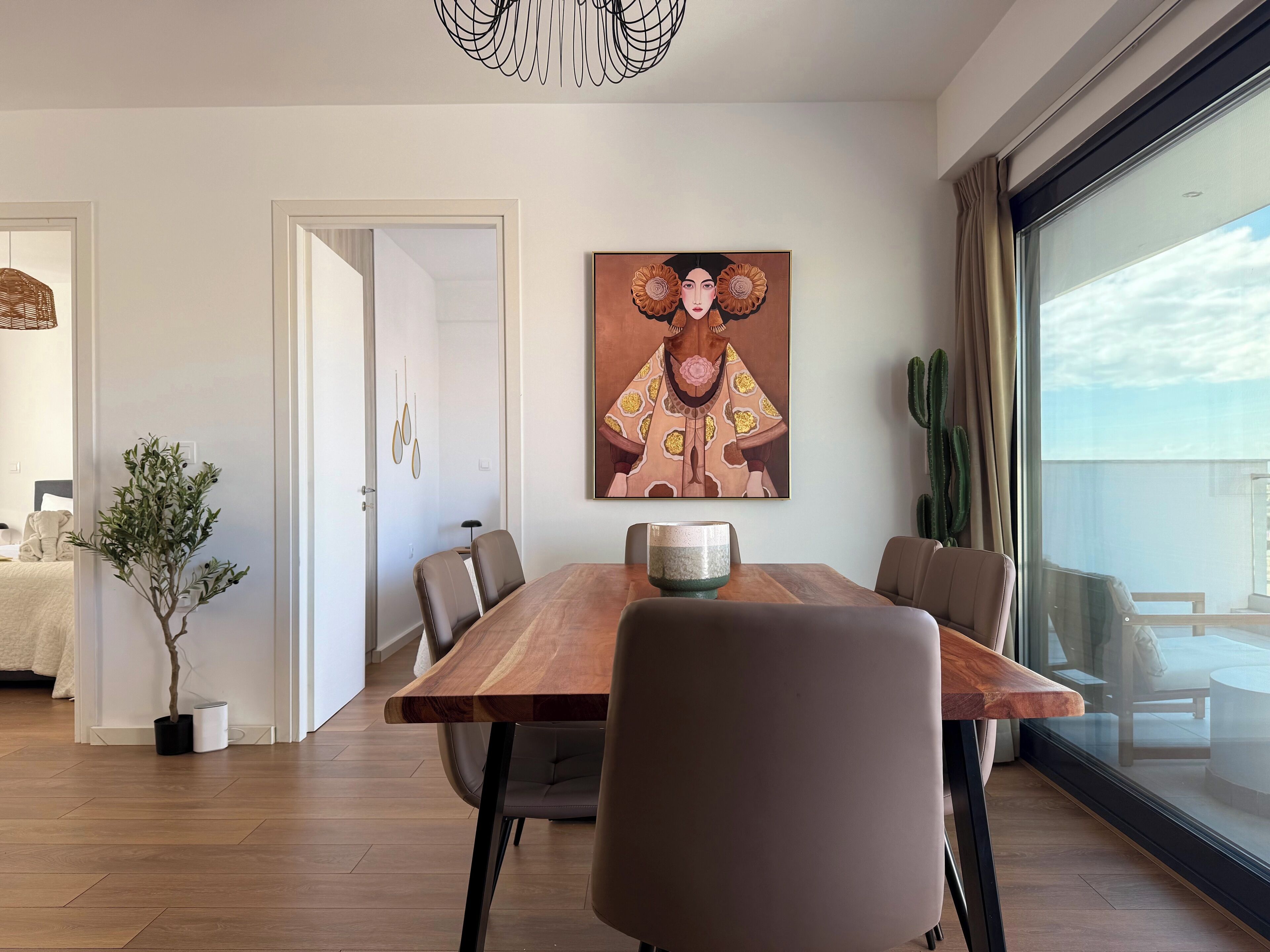 Un'elegante zona pranzo con tavolo in legno, sedie in pelle e un grande quadro appeso al muro.