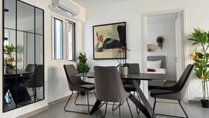 Un comedor moderno con una mesa y sillas negras, ventanas amplias y un cuadro en la pared.