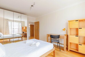 Hotellihuone, jossa on suuri sänky, työpöytä, tuoli, vaatekaappi ja peili.