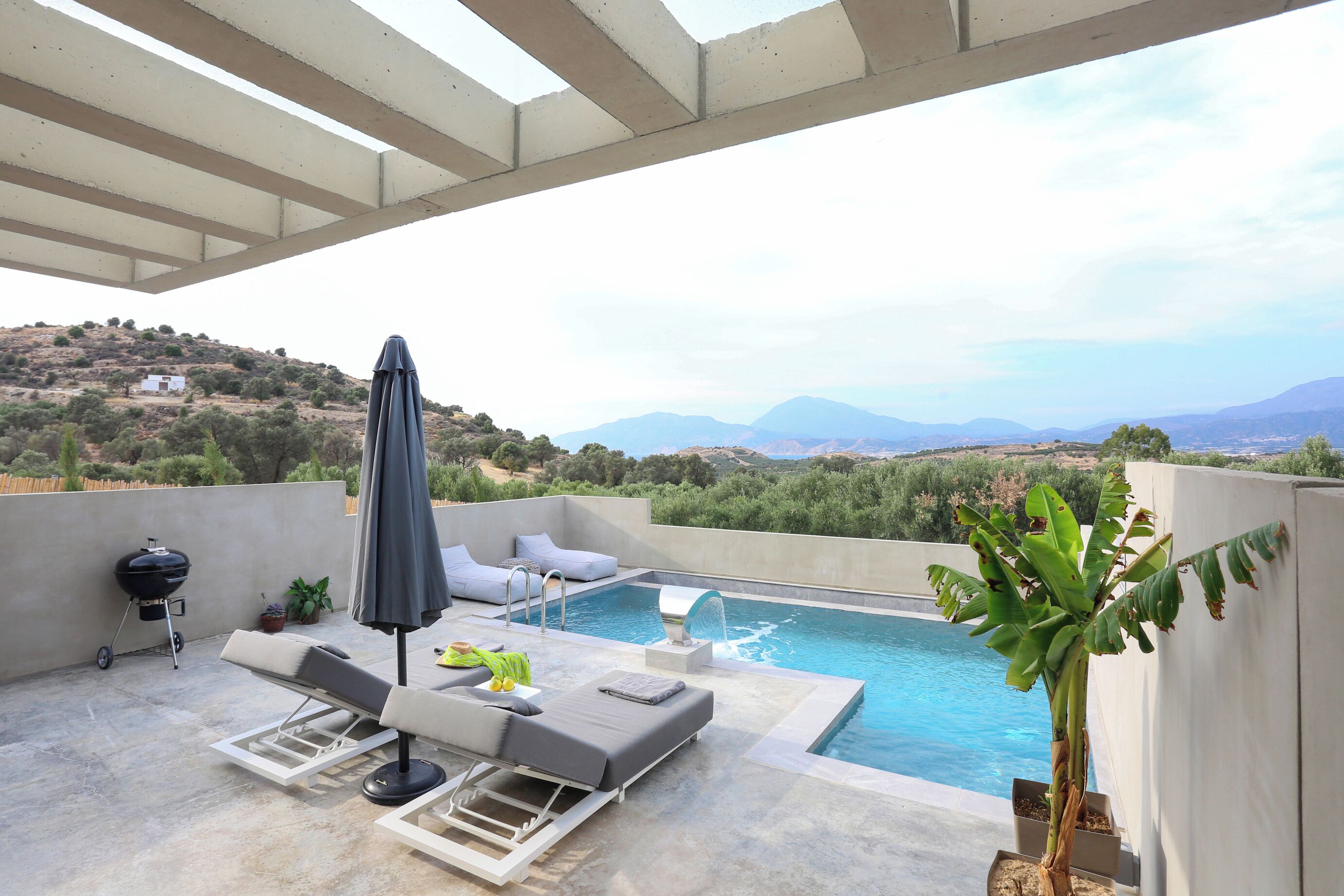 Un espace piscine aménagé sur le toit, avec des chaises longues, un barbecue et une vue sur le paysage environnant.