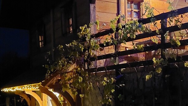 Un patio con un banco de madera, una mesa y un muro de piedra.