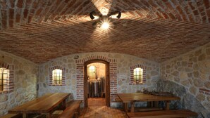 Un comedor rústico con paredes de piedra, bancos de madera y suelo de ladrillo.