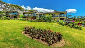 A hotel with multiple two-story buildings, a well-maintained lawn, and a variety of tropical plants. - Wailea Elua #2107 - Spacious, Stylish & Just Moments from Wailea Beach (Wailea, Maui)
