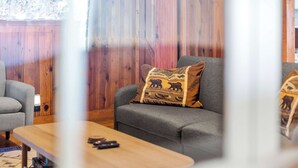 A living room with a grey sofa, a wooden coffee table, and a patterned throw pillow. - Rockaway Retreat (Rockaway Beach)