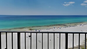 A beach view with a clear sky, a sandy shore, and a few umbrellas and beach chairs.