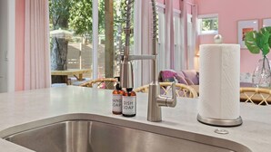 A kitchen sink with a modern faucet, two soap bottles labeled "HAND SOAP" and "DISH SOAP," and a paper towel holder. - Vivid ATX Vibes | Pools. Personality. Pure Bliss! (Austin)