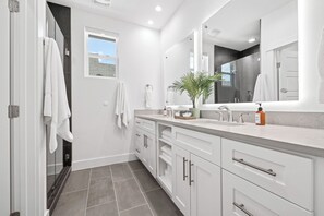 A modern bathroom with white cabinetry, a large mirror, and a potted plant. - Vivid ATX Vibes | Pools. Personality. Pure Bliss! (Austin)
