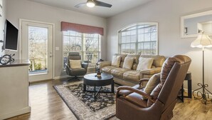 A living room with a sofa, armchair, coffee table, and a ceiling fan. - Stonebridge Condo on the Fairway (Branson West)