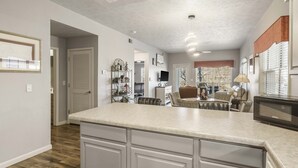 A kitchen with a large island, wooden flooring, and a dining area with a table and chairs. - Stonebridge Condo on the Fairway (Branson West)