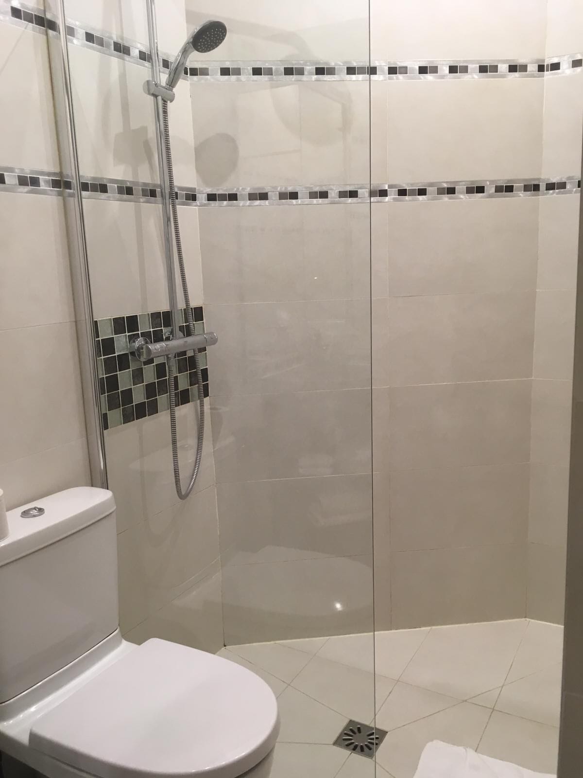 Un bagno moderno con cabina doccia in vetro, un water e pareti rivestite di piastrelle.
