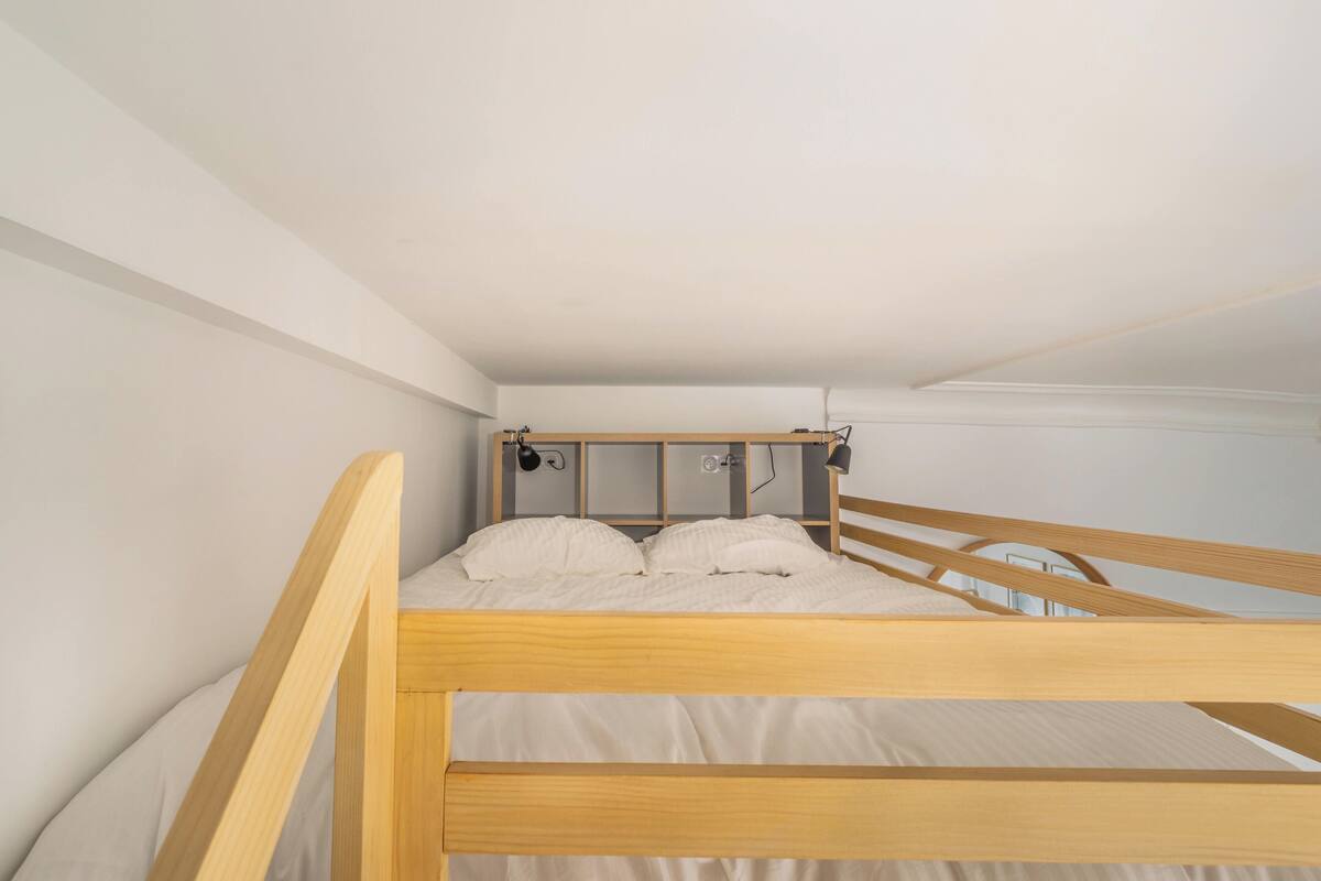 Une chambre simple, avec un lit une place, un cadre en bois, du linge de lit blanc et une petite table de chevet.