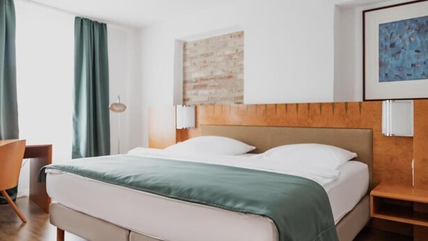 Une chambre d’hôtel avec un lit, un bureau et une chaise.