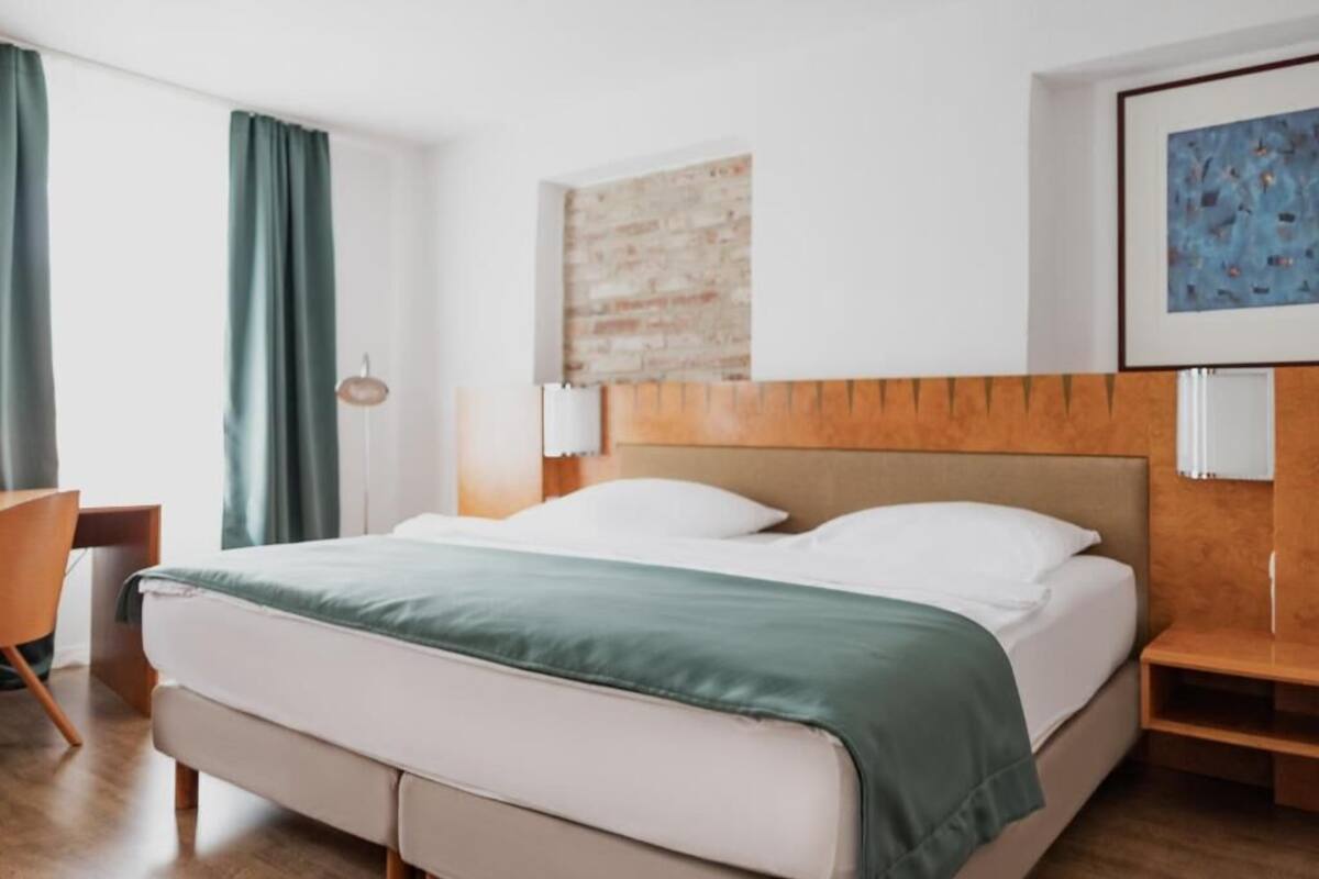 A hotel room with a bed, a desk, and a chair.