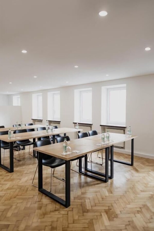A conference room with multiple tables and chairs, equipped with water bottles and papers. - Hotel Cristallo (Landshut)