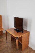 Un mueble de televisión de madera con un televisor de pantalla plana encima, colocado frente a una pared blanca.