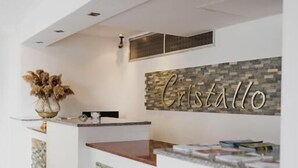 Un comptoir d’accueil avec un mur en pierre et, en arrière-plan, le nom « Cristallo ».