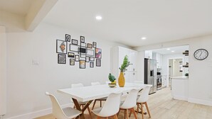 Una cocina moderna con armarios blancos, un refrigerador de acero inoxidable y un reloj en la pared.