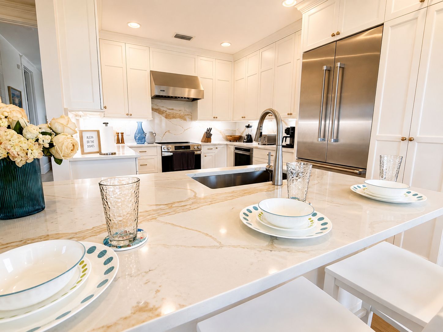 A modern kitchen with white cabinetry, stainless steel appliances, and a marble countertop.