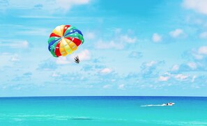 A person skydiving with a colorful parachute over a clear blue ocean. - Gulf Views 🌊 | Elevator 🏡 | 1 Minute to Beach 🌴| Heated Pool & Spa 🌅Sunsets (Anna Maria)