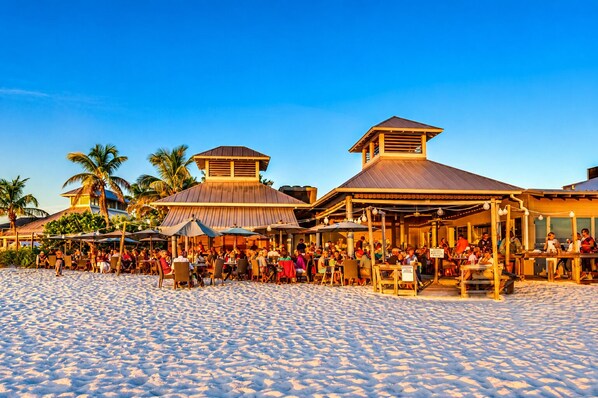 A beachfront restaurant with outdoor seating and a covered patio area.