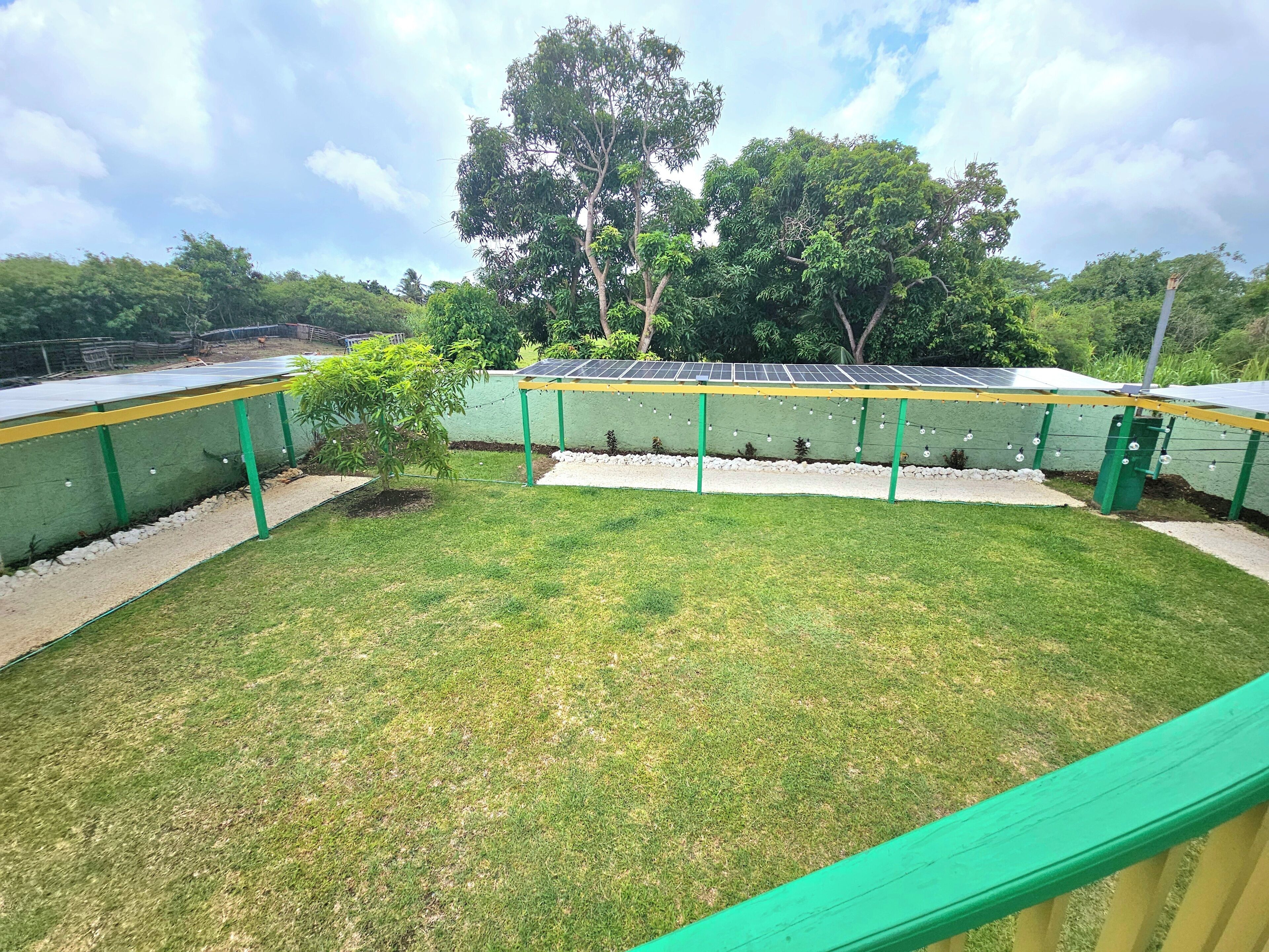 A solar panel installation with a green fence and a grassy area.