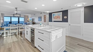 A modern kitchen with white cabinetry, a marble countertop, and a view of the ocean.