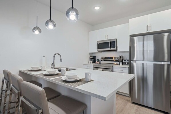 A modern kitchen with a central island, stainless steel appliances, and pendant lighting.