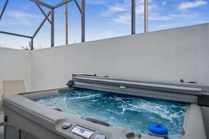 Un bain à remous doté d’un panneau de commande, entouré d’un mur blanc et de poutres métalliques.