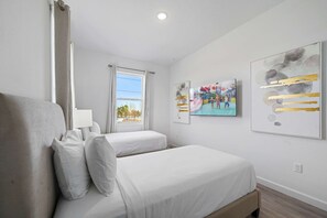 Habitación de hotel con dos camas, una ventana y obras de arte en las paredes.