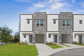 Un immeuble résidentiel moderne à plusieurs étages, doté d’un toit plat, d’une façade en pierre et d’une pelouse bien entretenue.
