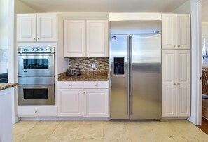 A kitchen with white cabinets, a stainless steel refrigerator, and a built-in oven. - Spacious Beachfront Penthouse w/ Stunning Views & Great Amenities! (Destin)