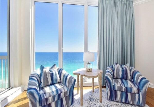 A room with two armchairs, a small table with a lamp, and a view of the ocean. - Spacious Beachfront Penthouse w/ Stunning Views & Great Amenities! (Destin)