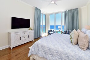 A bedroom with a large bed, a television, a white dresser, and a view of the ocean. - Spacious Beachfront Penthouse w/ Stunning Views & Great Amenities! (Destin)
