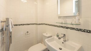 A bathroom with a glass shower enclosure, a white toilet, and a sink with a mirror above it. - Host & Stay | Glaisdale at the Sandbeck (Whitby)