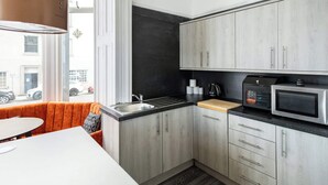 Eine moderne Küche mit grauen Schränken, einer schwarzen Arbeitsplatte und einer Mikrowelle.