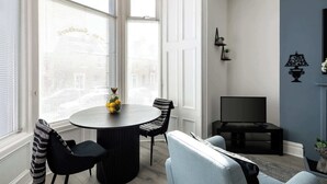 Un coin repas avec une table ronde et des chaises, un téléviseur et un mur d’accent bleu.