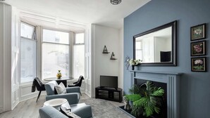 Un salon avec une cheminée, un ensemble de canapés, un téléviseur et une table à manger.