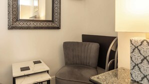 A small, compact room with a grey armchair, a small table with a tablet, and a patterned side table. - Host & Stay | Ruswarp Studio at the Sandbeck (Whitby)