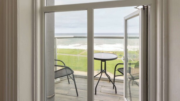 A balcony with a glass door, a small round table, and two chairs. - Host & Stay | Ruswarp Studio at the Sandbeck (Whitby)