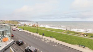A coastal road with a view of the sea, a pedestrian path, and parked cars. - Host & Stay | Ruswarp Studio at the Sandbeck (Whitby)