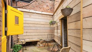 Una habitación de madera con una puerta amarilla, sillas de mimbre y plantas en macetas.